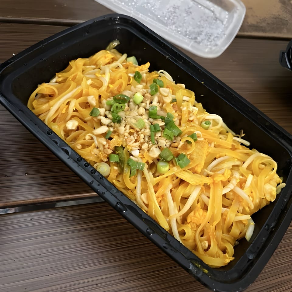 Thai Wok ToGo's Pad Thai noodles with bean sprouts, crushed peanuts, and green onions in a black container.