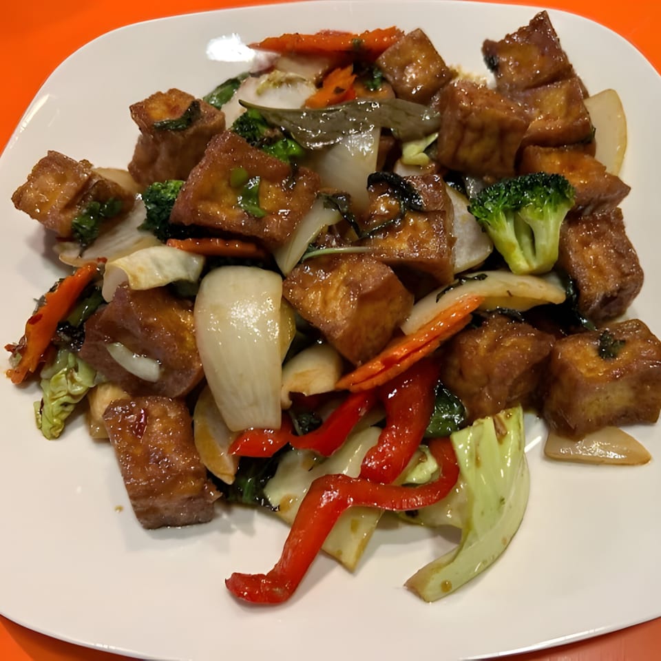 Thai Wok ToGo's stir-fried tofu with broccoli, carrots, onions, and red bell peppers on a white plate.