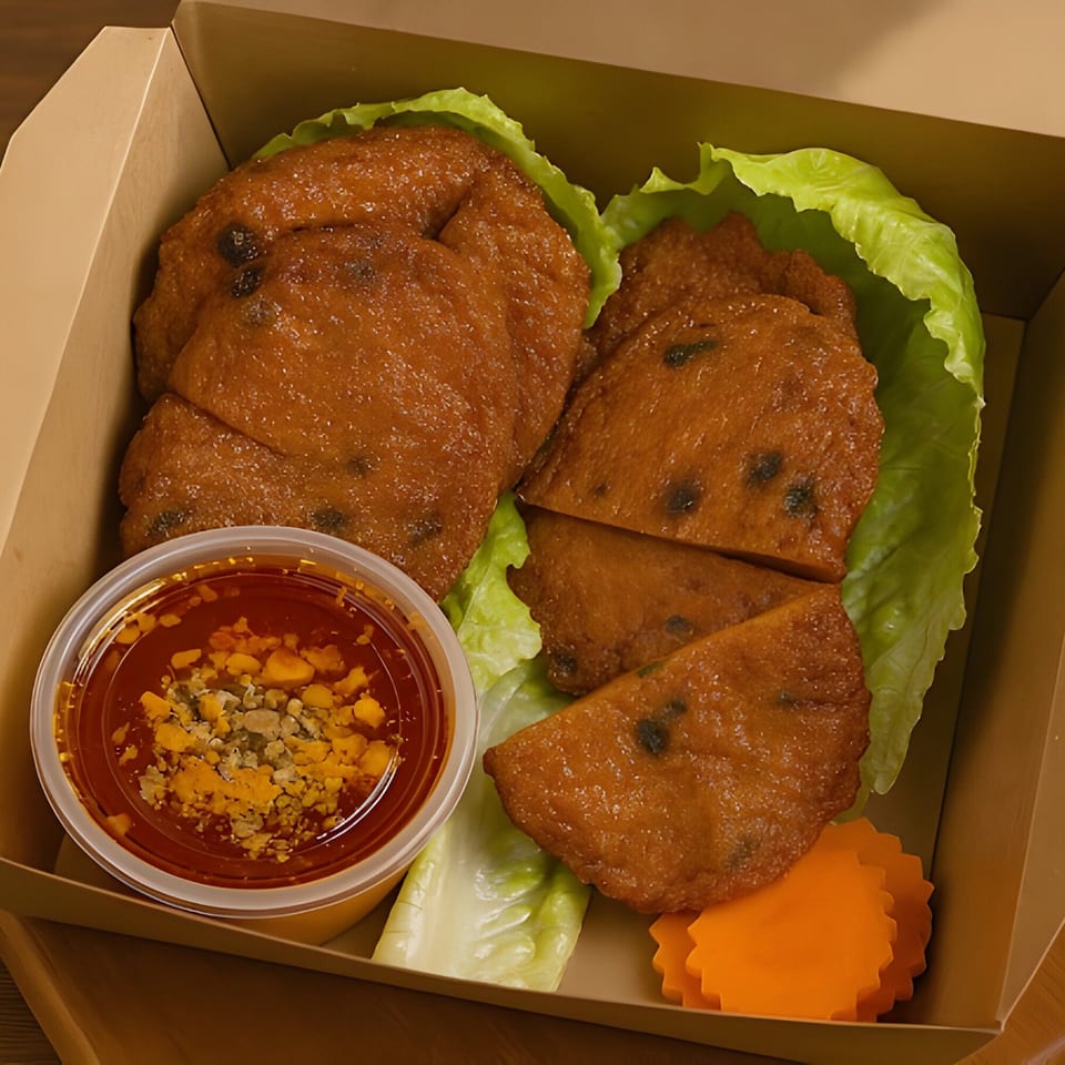 Thai Wok ToGo's fried fish cakes with chili sauce, lettuce, and carrot garnish in a takeout box.